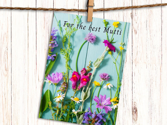 Greeting card with floral design and text 'For the best Mutti' on a wooden background