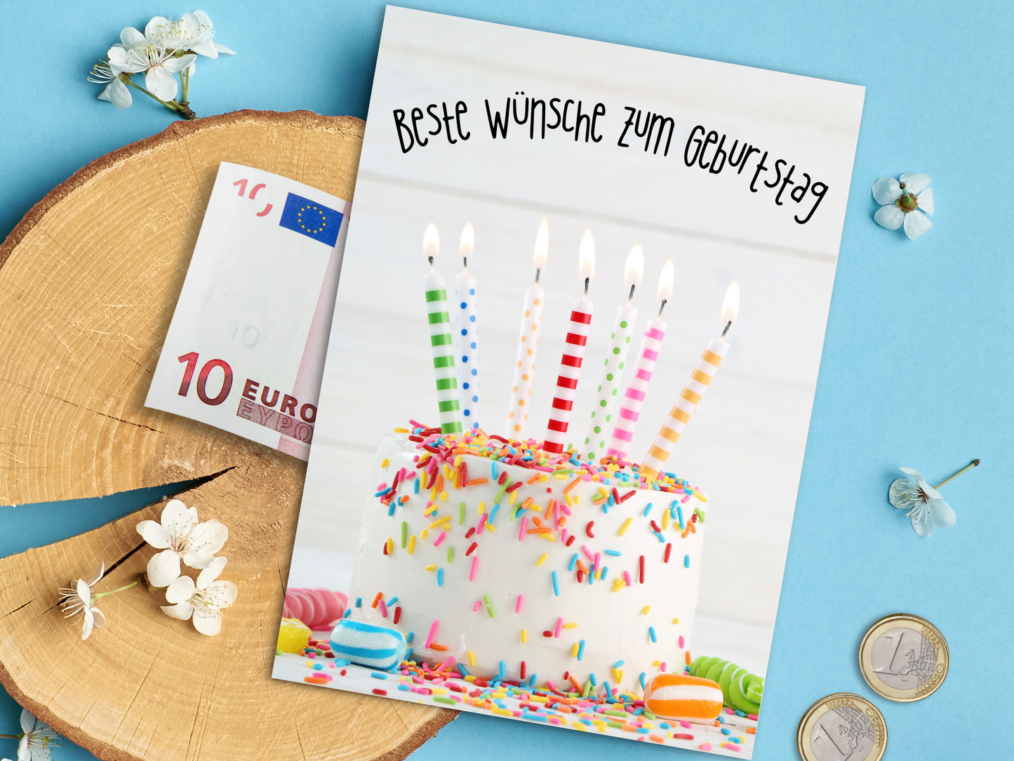 German Birthday card with picture of white cake with colorful sprinkles, candy, and candles; text across the top of card "Beste Wünsche zum Geburtstag" means best wishes for your Birthday.