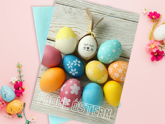 Easter card with colorful eggs on a bleached wood background. One of the Easter eggs has a face of a bunny and paper bunny ears. 