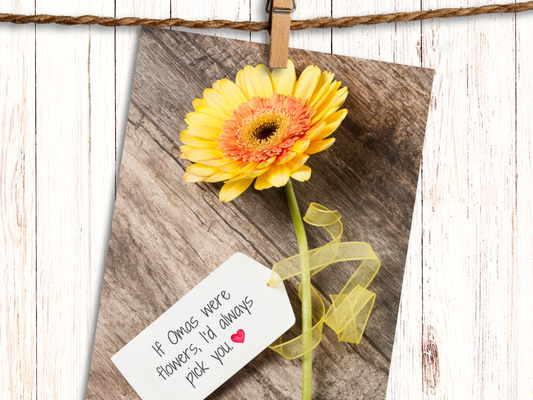 Greeting card featuring a yellow Gerbera daisy against a wood background with a tag, attached with yellow ribbon, that says "If Omas were Flowers, I'd always pick you" and heart emoji.